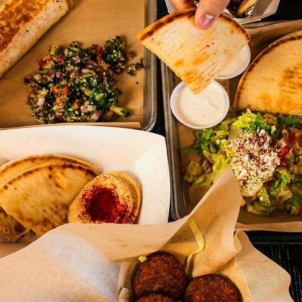Overhead view of various Middle Eastern dishes, including wraps, rice, meat, salad, hummus, and falafel.