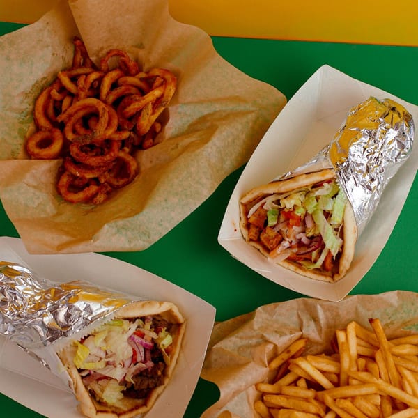 Two foil-wrapped gyros, curly fries, and regular fries on a green and yellow background.
